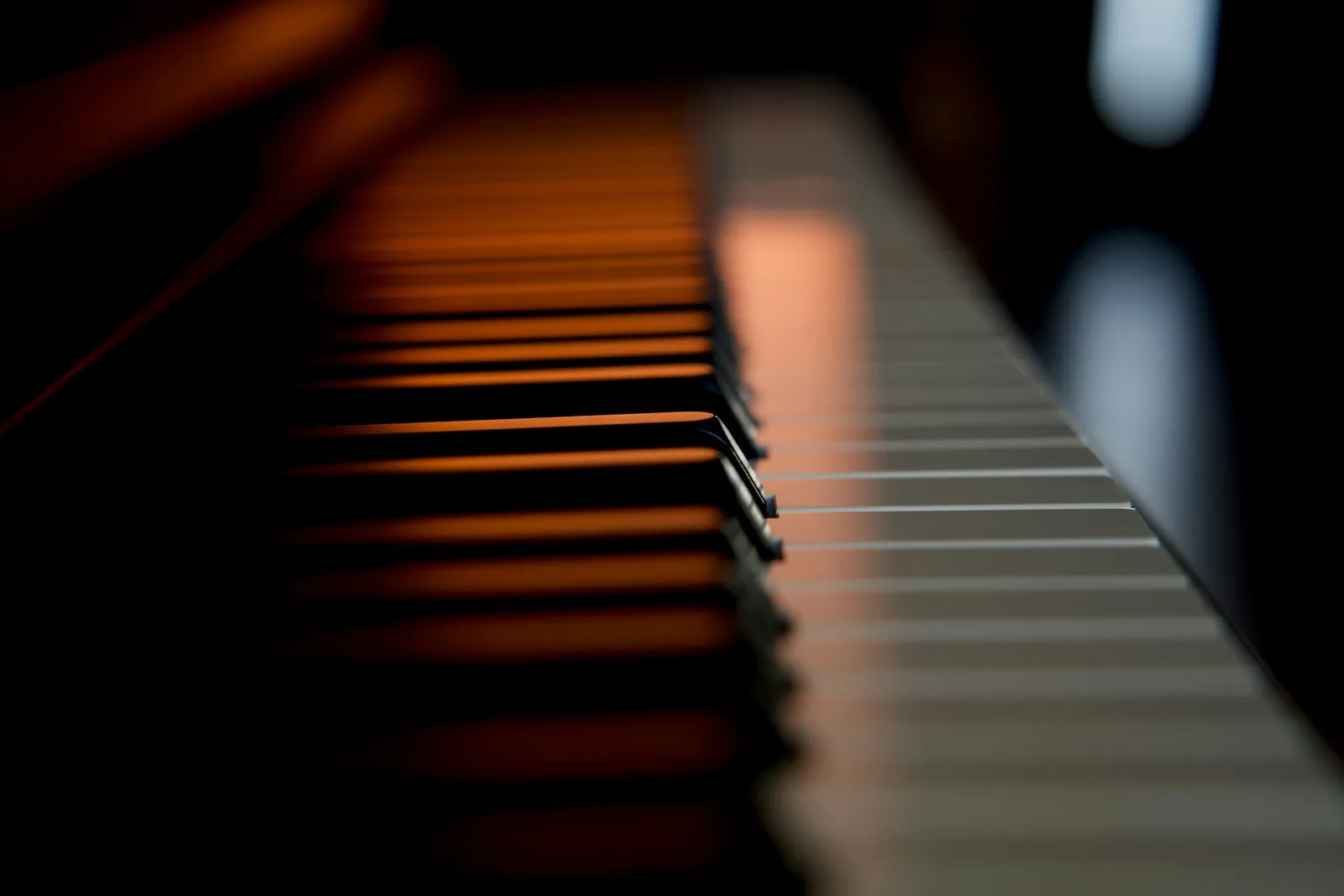 A close view along piano keys in soft amber light.